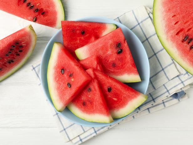 Composition with plate of fresh watermelon on white wooden background, top view