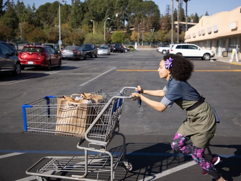 Chef Gabrielle running back to her station with a cart of groceries, as seen on Supermarket Stakeout, Season 3.