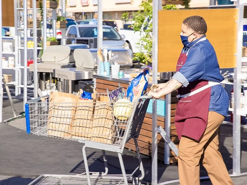 Chef Mel arriving back at her station with cart full of groceries, as seen on Supermarket Stakeout, Season 3.