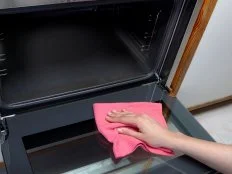 Woman cleaning oven using microfiber rag.