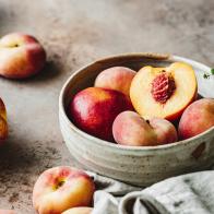 Close-up of ripe peaches in a bowl on kitchen counter.