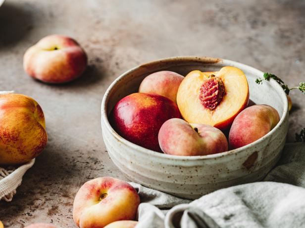 Close-up of ripe peaches in a bowl on kitchen counter.