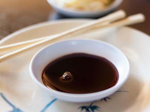 Bowl of soy sauce with chopsticks on table