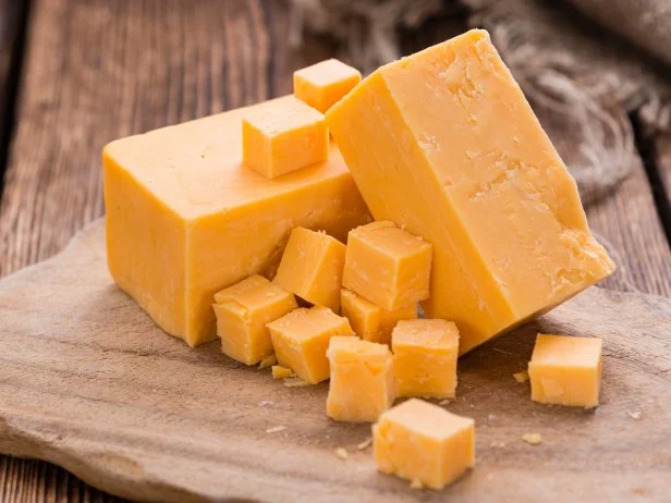 Portion of Cheddar (detailed close-up shot) on vintage wooden background