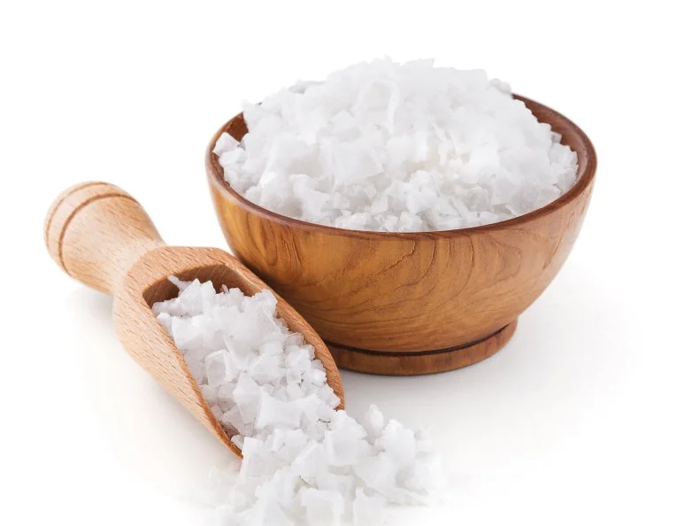 Cyprus sea salt flakes in a wooden bowl isolated on white background