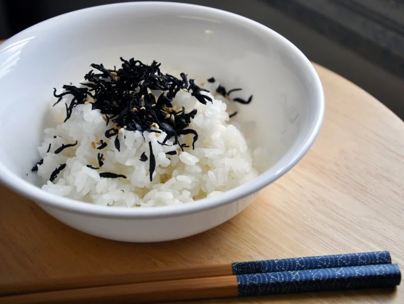 Rice with furikake in bowl on table with chopsticks