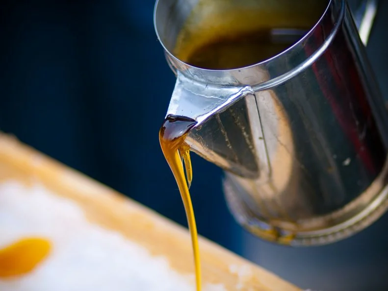 Maple syrup being poured on ice at a sugar shack