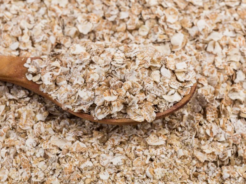 Whole grain, rolled oats flakes with wooden spoon