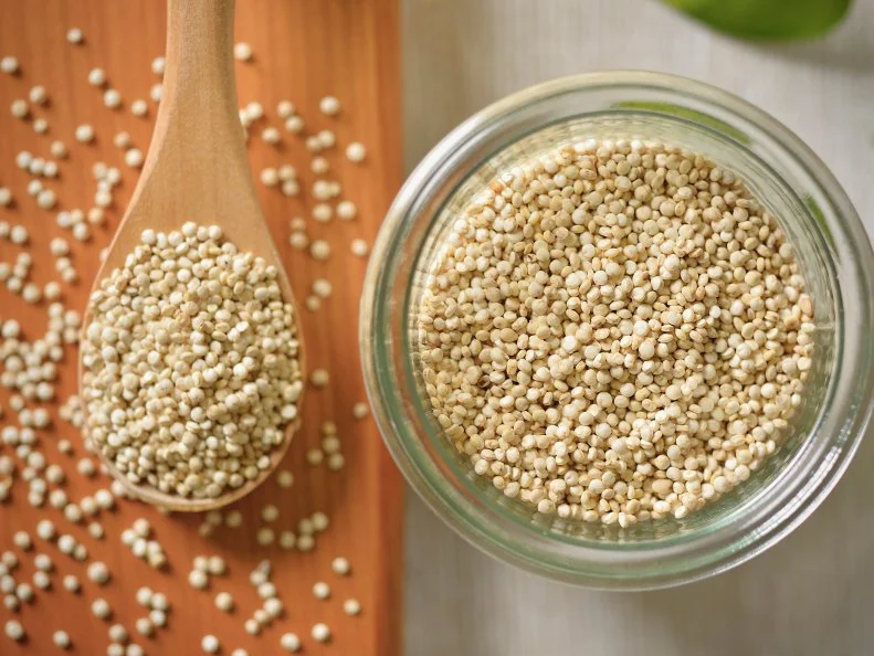 Quinoa is in the glass container and a wooden spoon,Super food