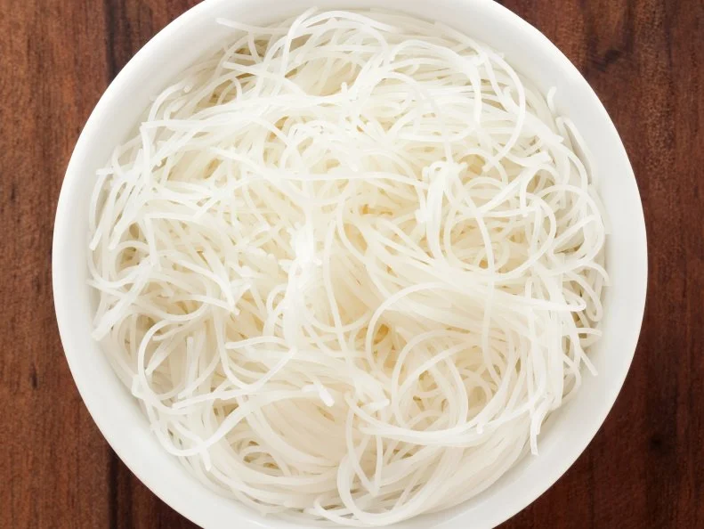 Top view of white bowl full of  rice noodles