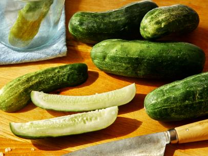 Man cutting a cucumber with a chef's knife. Thin slices of the