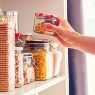 A Man Takes or Places Glass Jars Filled With Legumes From A Shelf In The Pantry