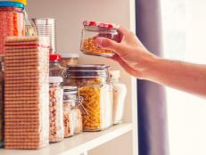 A Man Takes or Places Glass Jars Filled With Legumes From A Shelf In The Pantry