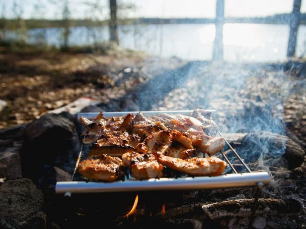 Chicken Meat on fire camp. Portable Stainless Steel BBQ Grill hiking concept. cooking on wild nature.