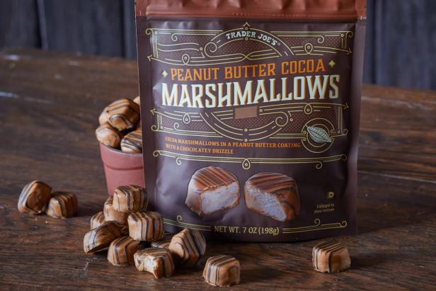 Trader Joe's Peanut Butter Cocoa Marshmallows piled on wood surface, one bitten into
