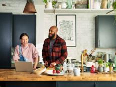 Cheerful couple laughing whilst making dinner, multitasking, cooperation, teamwork, fun