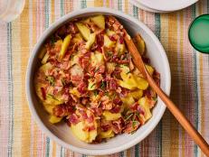 Toss Yukon gold potatoes with Dijon mustard, vinegar, thick-cut bacon, chives and seasoning for this classic German Potato Salad recipe from Food Network.