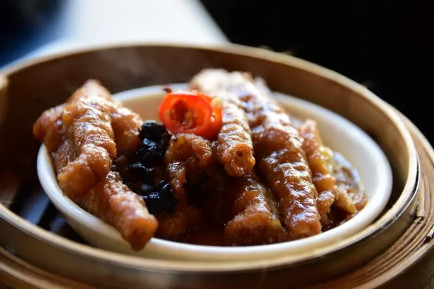 Close up of a plate of Chinese spicy chicken feet in a bamboo steamer