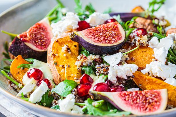 Warm autumn quinoa salad with baked vegetables (sweet potato, Brussels sprouts), figs, feta cheese and pomegranate, close-up.