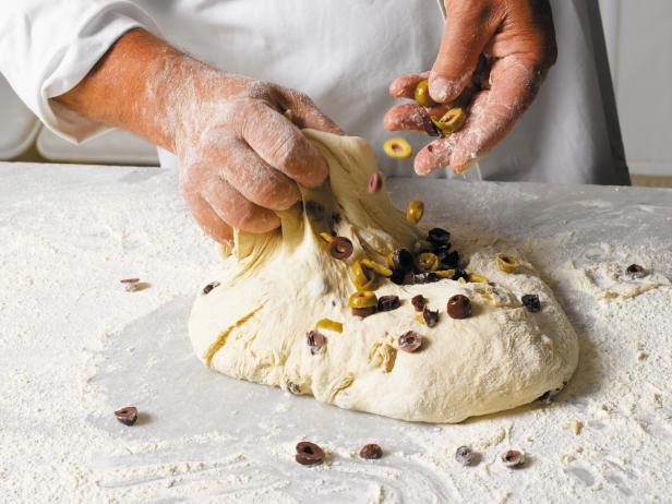 Close up of a baker making bread with olives in