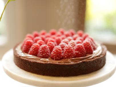 Close up, side on shot of chocolate tart on white cake stand, as seen on Mary McCartney Serves It Up, season 3.