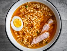 Flat top lay view closeup of Japanese ramen noodle instant soup in bowl as asian meal with texture of cooked boiled egg and pork slices toppings floating