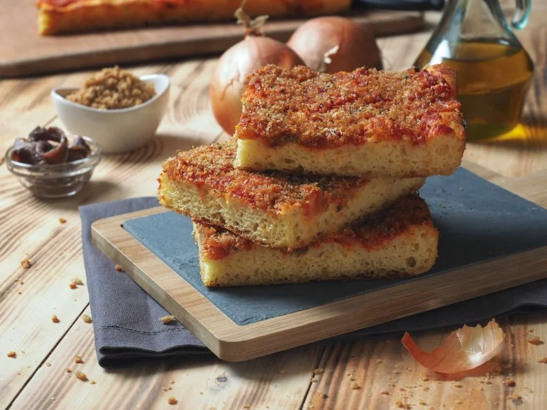 Sicilian italian traditiona pizza focaccia bread called sfincione, preppared with onions, tomato sauce, anchovies, caciocavallo cheese and bread crumbs