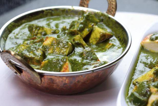 A bowl of Palak Paneer made of Paneer cheese dipped in mildly spiced Spinach gravy on wooden background.