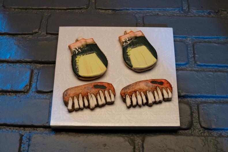 Contestant Justine Banks' round 1 dish, A diseased Jaw and a gangrenous big toe, peanut butter cookie with maple royal icing, as seen on Halloween Cookie Challenge, Season 1.
