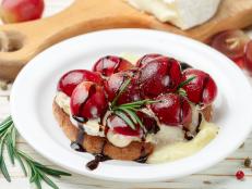 Bruschetta of Camembert or brie cheese with red grapes, rosemary and balsamic. crostini. Gourmet wine snacks for foodies. Italian antipasti. Selective focus