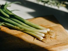 Bunch of green onions on a wood cutting board