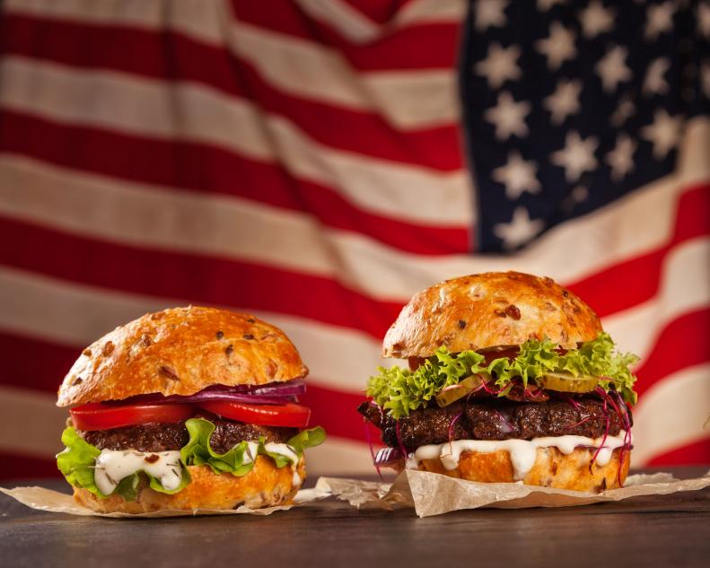 Delicious hamburgers served on wooden planks. Flag of USA as background