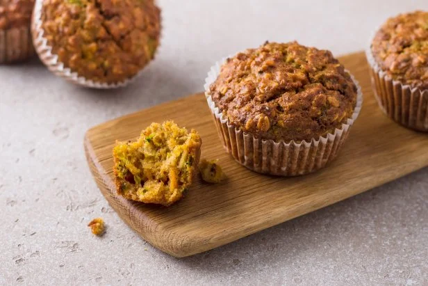 Homemade freshly baked pumpkin muffins with oatmeal and nuts on a beige textured background