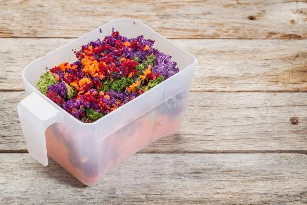 colorful juicer pulp after juicing raw vegetables (carrot, red beat, cucumber, kale, red cabbage) - a plastic cup against barn wood background
