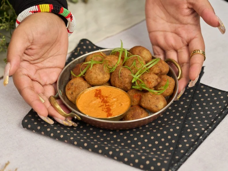 3/4 of Kenya T. Parham’s hands holding Crispy Akara, as seen on The Kwanzaa Menu.