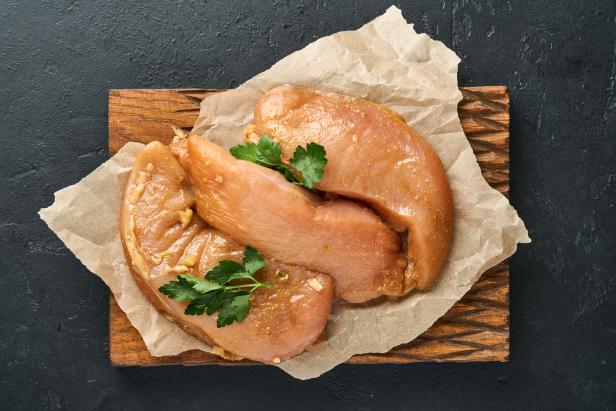 Raw marinated chicken meat with garlic, honey, ginger, pepper, soy sauce or teriyaki sauce on dark slate, stone or concrete background. Top view with copy space.