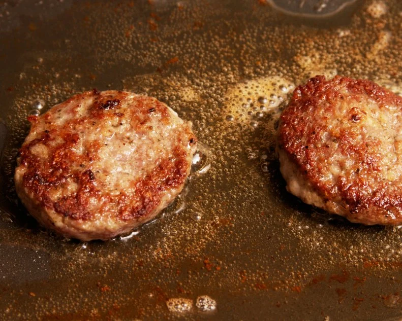 two cooking sausage patties on a skillet. 
