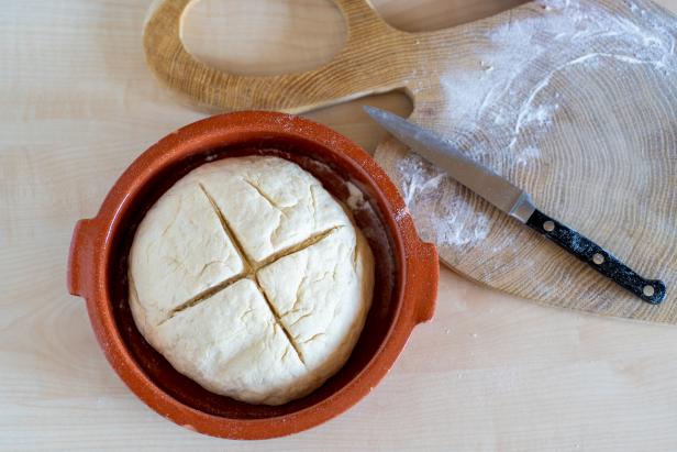 Bread dough with cross cutted on top on healthy, home made irish soda bread in a red ceramic bowl