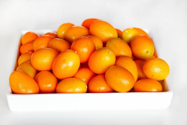 Kumquats piled on a white ceramic tray