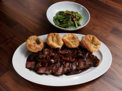Anne Burrell’s Dry-Rubbed Ribeye, Rosemary and Gruyere Yorkshire Pudding and Sauteed Sugar Snap Peas with Bacon and Mint is displayed, as seen on Worst Cooks in America, Season 25.