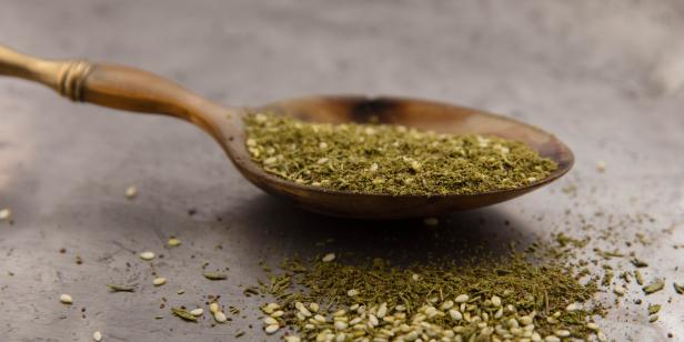 Za'atar. Old spoon filled with za'atar on a tin plate. Za'atar is mix of sesame seed, sumac and thyme.