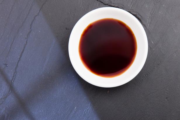 A bowl of soy sauce. White bowl on slate plate. High point of view. Light effect.