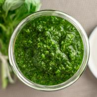 Fresh homemade basil pesto sauce in a glass jar viewed from above. Originally from italy, pesto is commonly made with basil and used as a sauce for pasta.