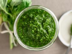 Fresh homemade basil pesto sauce in a glass jar viewed from above. Originally from italy, pesto is commonly made with basil and used as a sauce for pasta.
