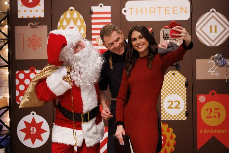 Bobby Flay and co-host Sophie Flay pose for a photo with Santa Claus during round three, as seen on Beat Bobby Flay Holiday Throwdown, Season 2.