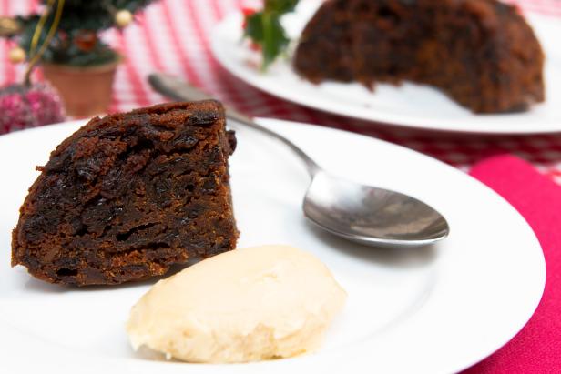 A traditional British Christmas steamed pudding decorate with holly served with brandy sauce