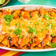 Homemade chicken enchiladas garnished with green onions and cilantro in a white casserole dish.