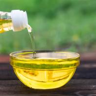 Pouring cooking oil from jug into bowl on wooden table. pouring oil from a bottle into a glass bowl on a wooden table. the process of cooking food.