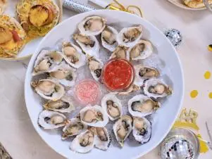 Host Selena Gomez and Chef Eric Adjepong's final dish "Oysters with a champagne mignonette and cocktail sauce", as seen on Selena + Chef: Home for the Holidays, Season 5.