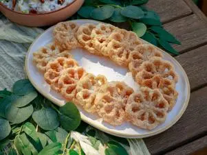 Host Selena Gomez and Chef Claudette Zepeda's dish "Buñuelos de Aire (rosette fritters with cinnamon sugar)", as seen on Selena + Chef: Home for the Holidays, Season 5.